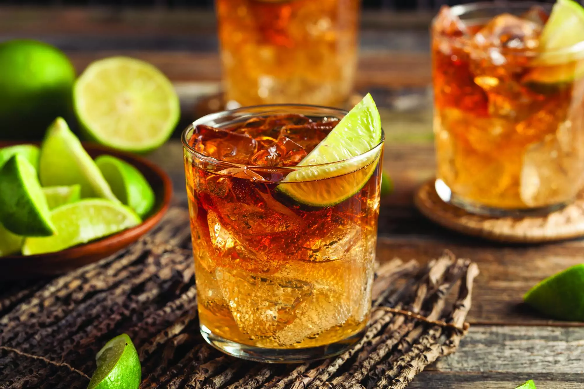 photo of full glass of amber bourbon with ice and lime